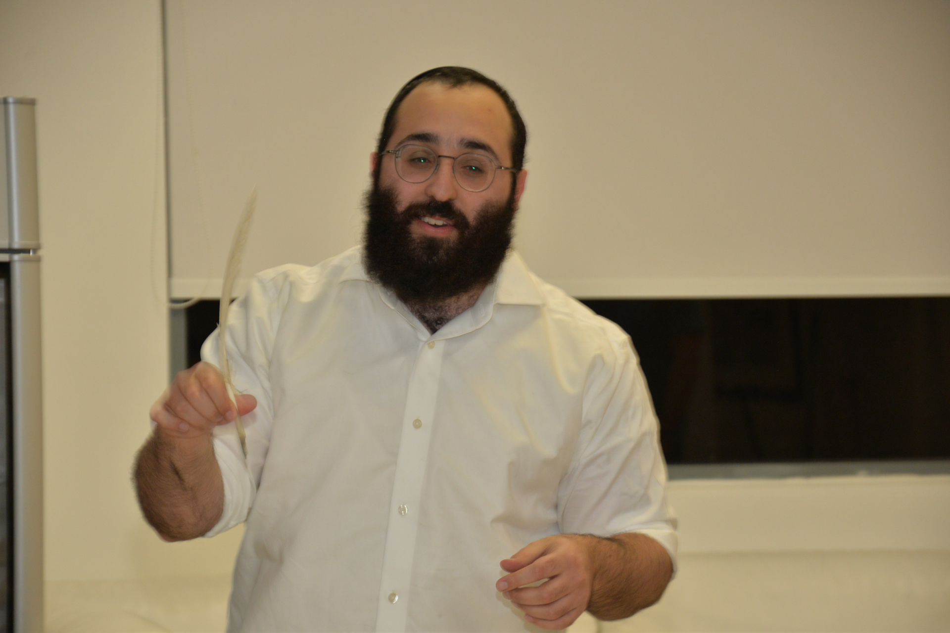 Levi Backman, Certified Sofer STaM, holding a quill