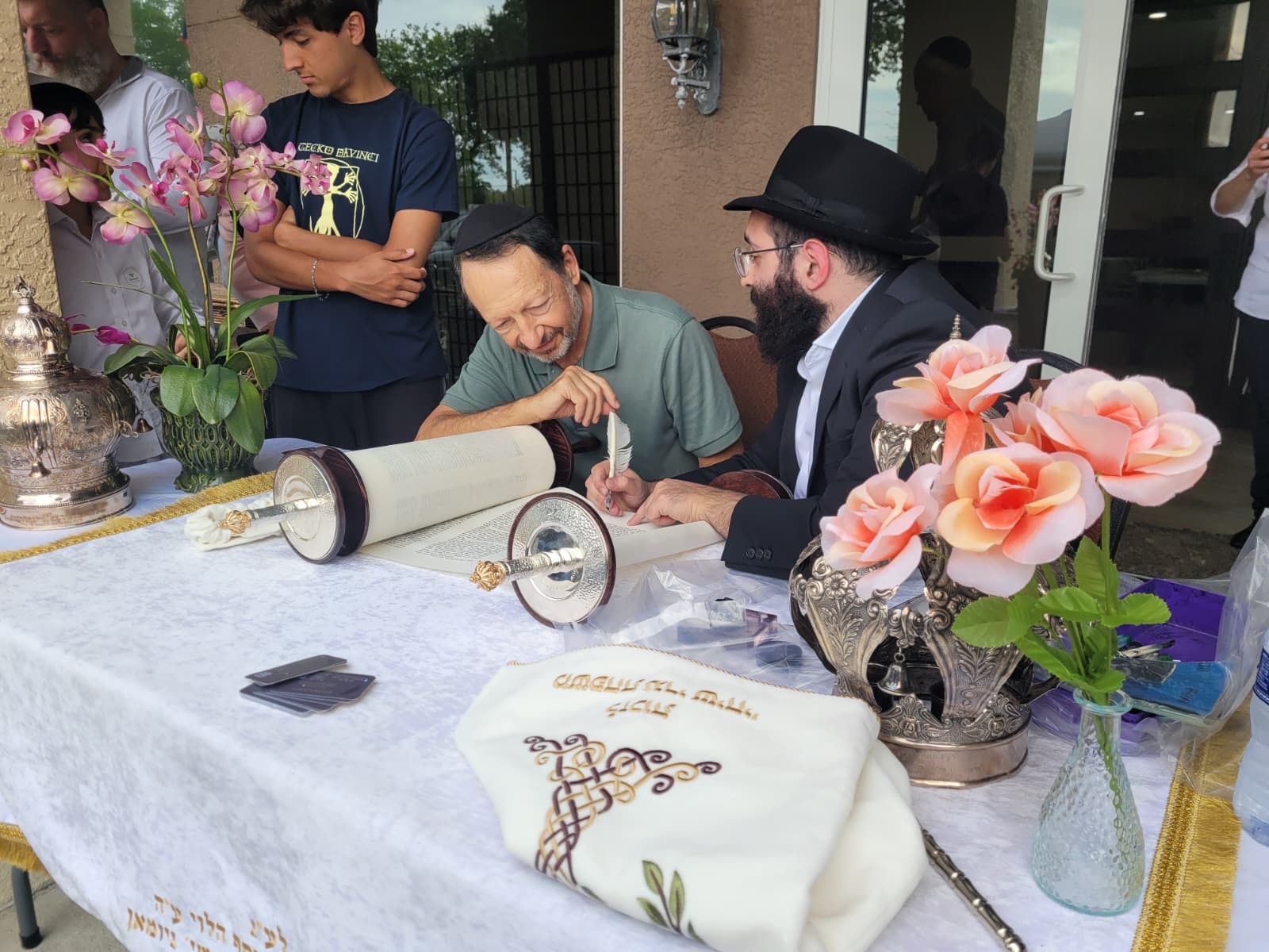 Community member writing a letter in a Sefer Torah