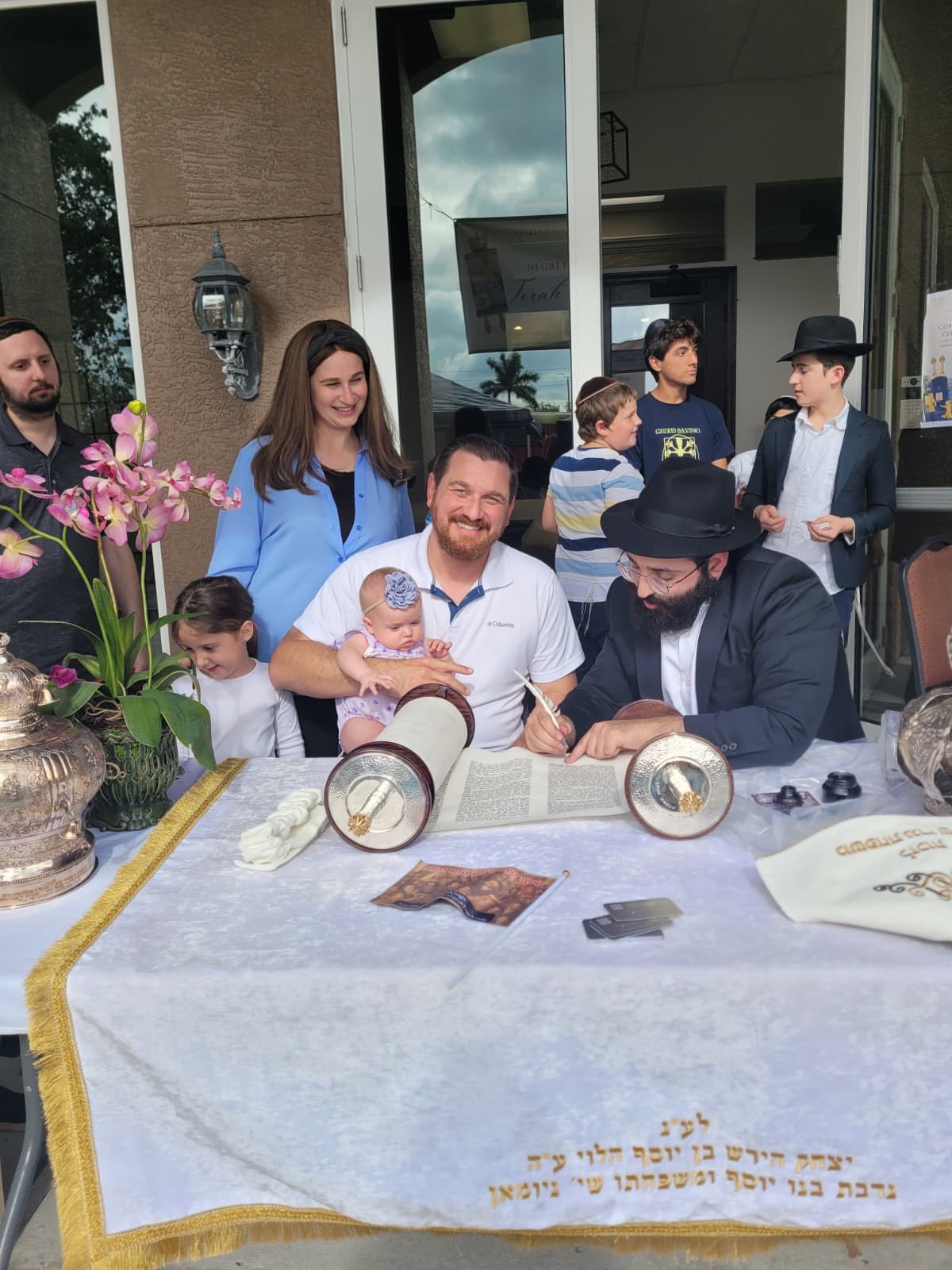 Family writing a letter in a Sefer Torah together